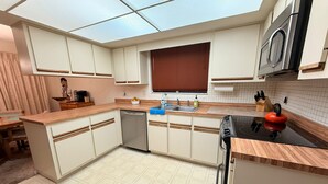 Una cocina moderna con armarios blancos, lavavajillas de acero inoxidable, estufa negra y encimera de madera.