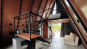 Um quarto moderno estilo loft com teto de madeira, um mezanino, uma escada e uma área de estar aconchegante.