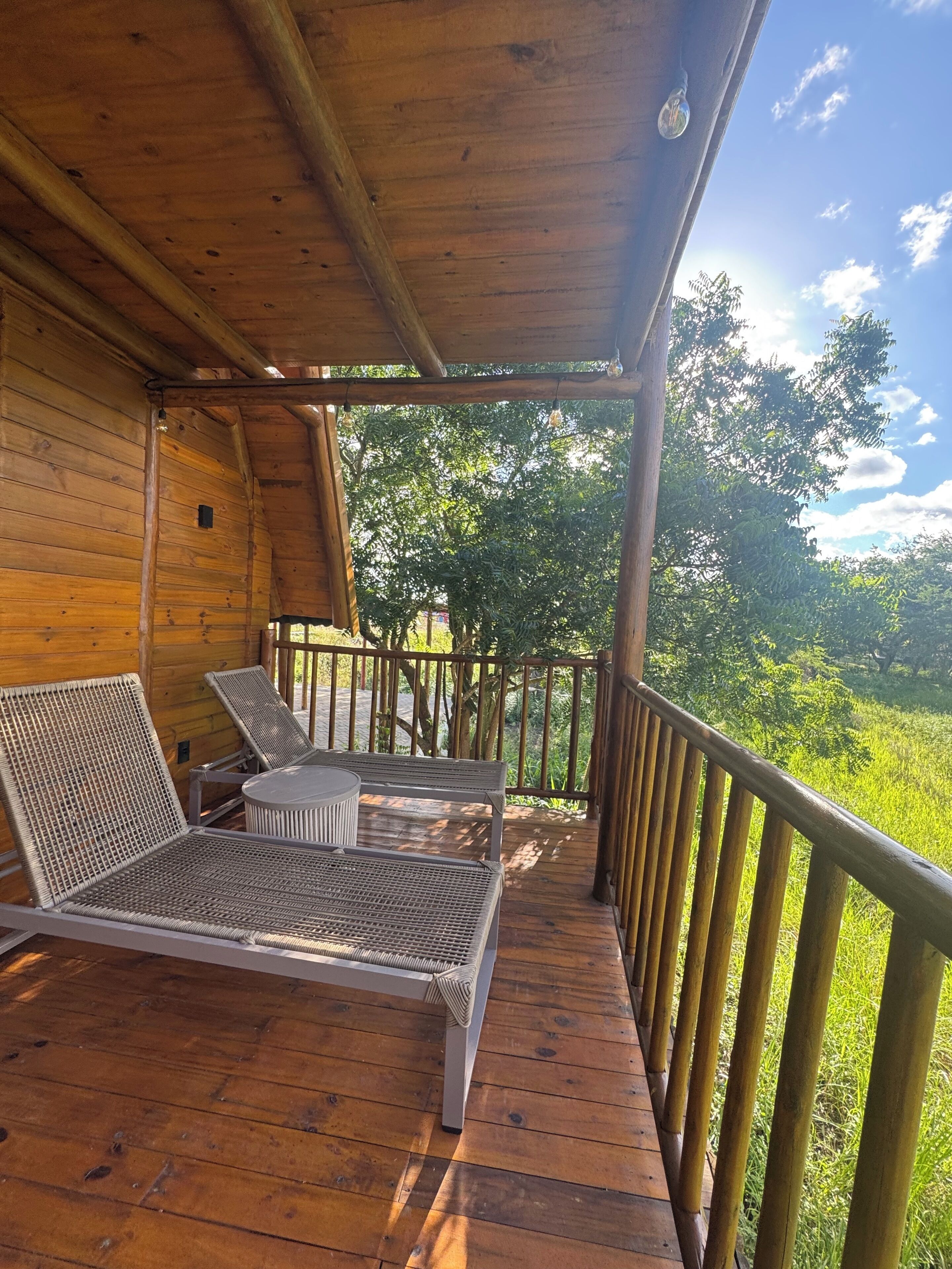 A wooden deck with two reclining chairs and a table, surrounded by a wooden railing.