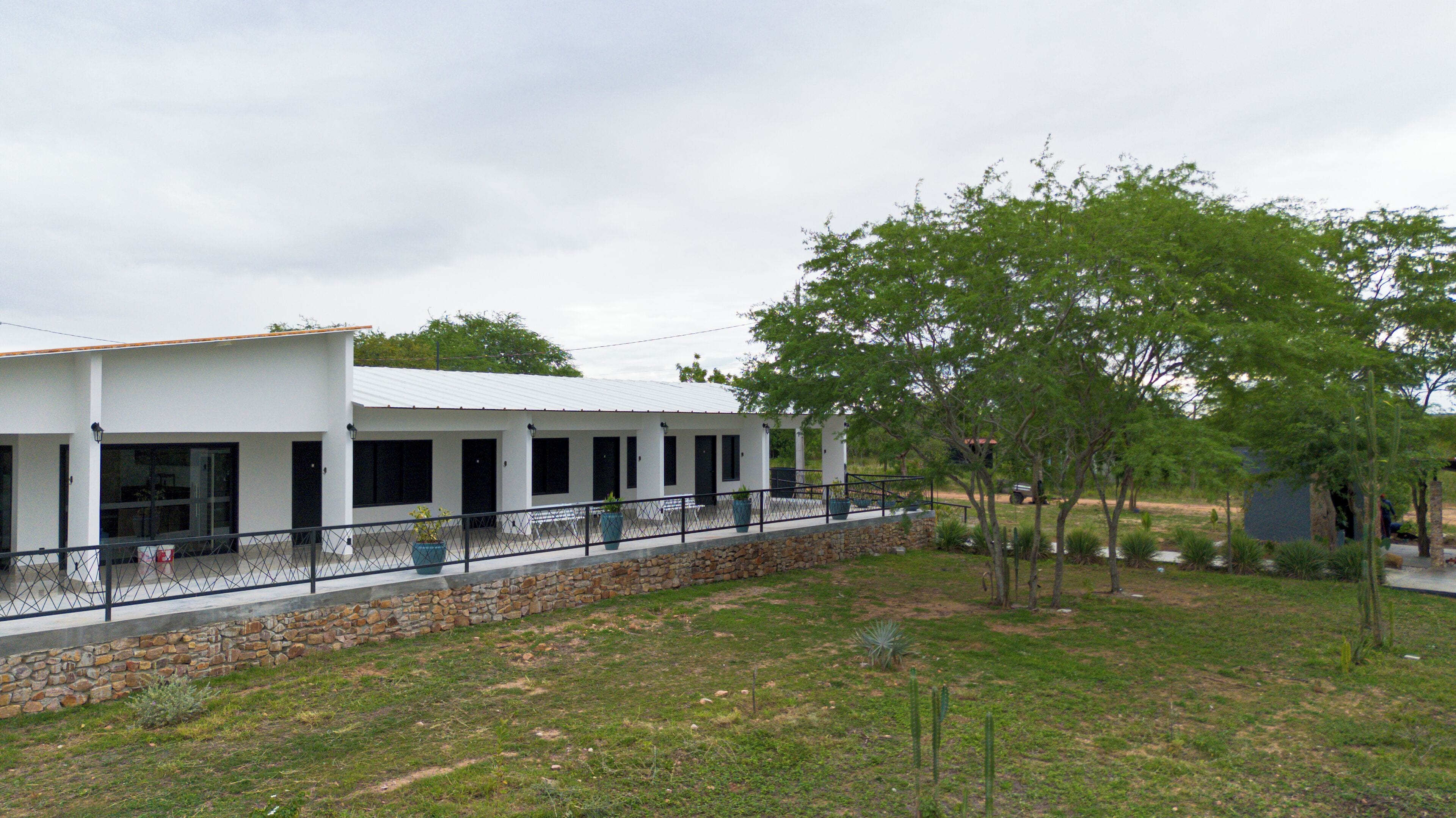 A modern building with a white exterior, large windows, and a covered outdoor area.