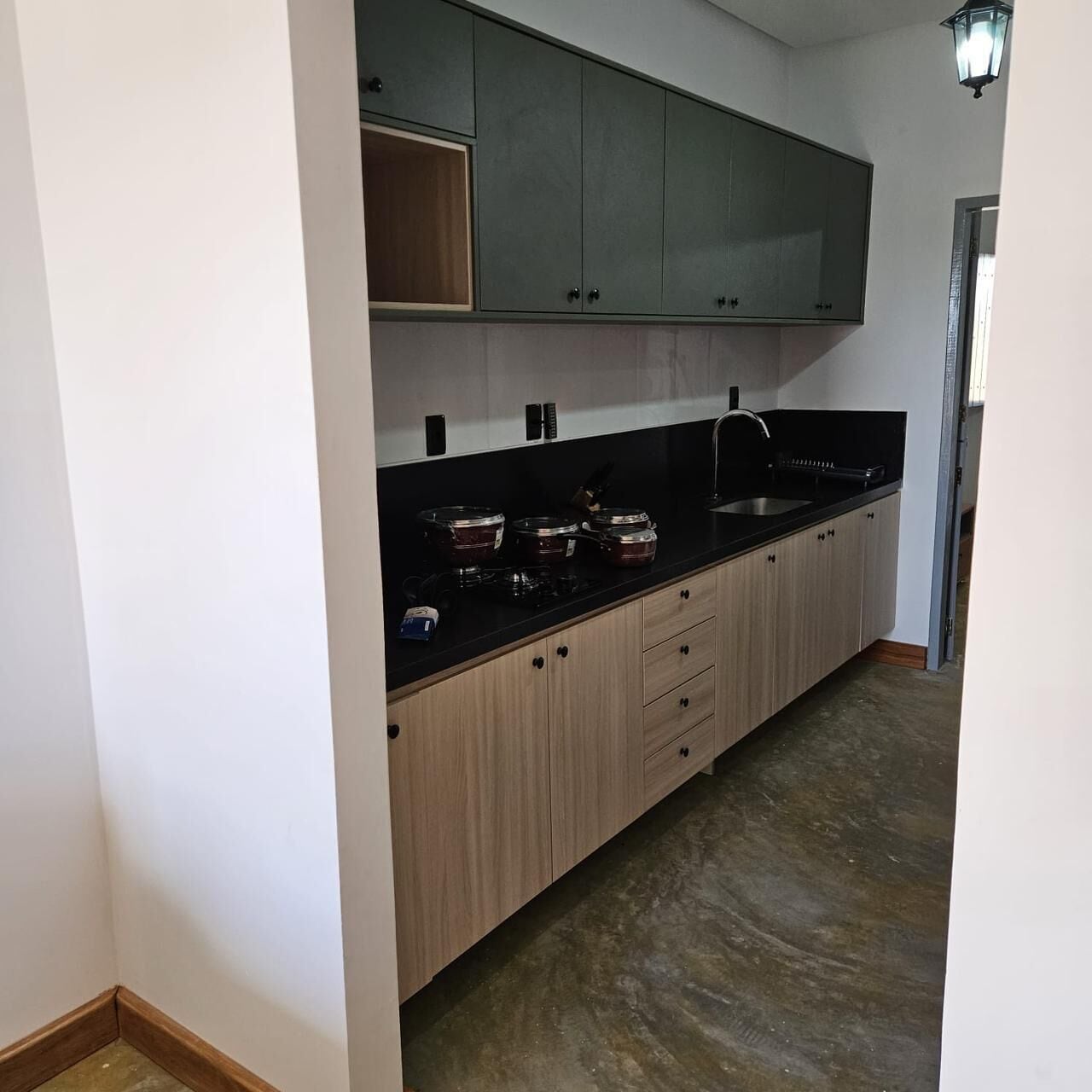 Una cocina con gabinetes de madera clara, encimera negra y pileta de acero inoxidable.