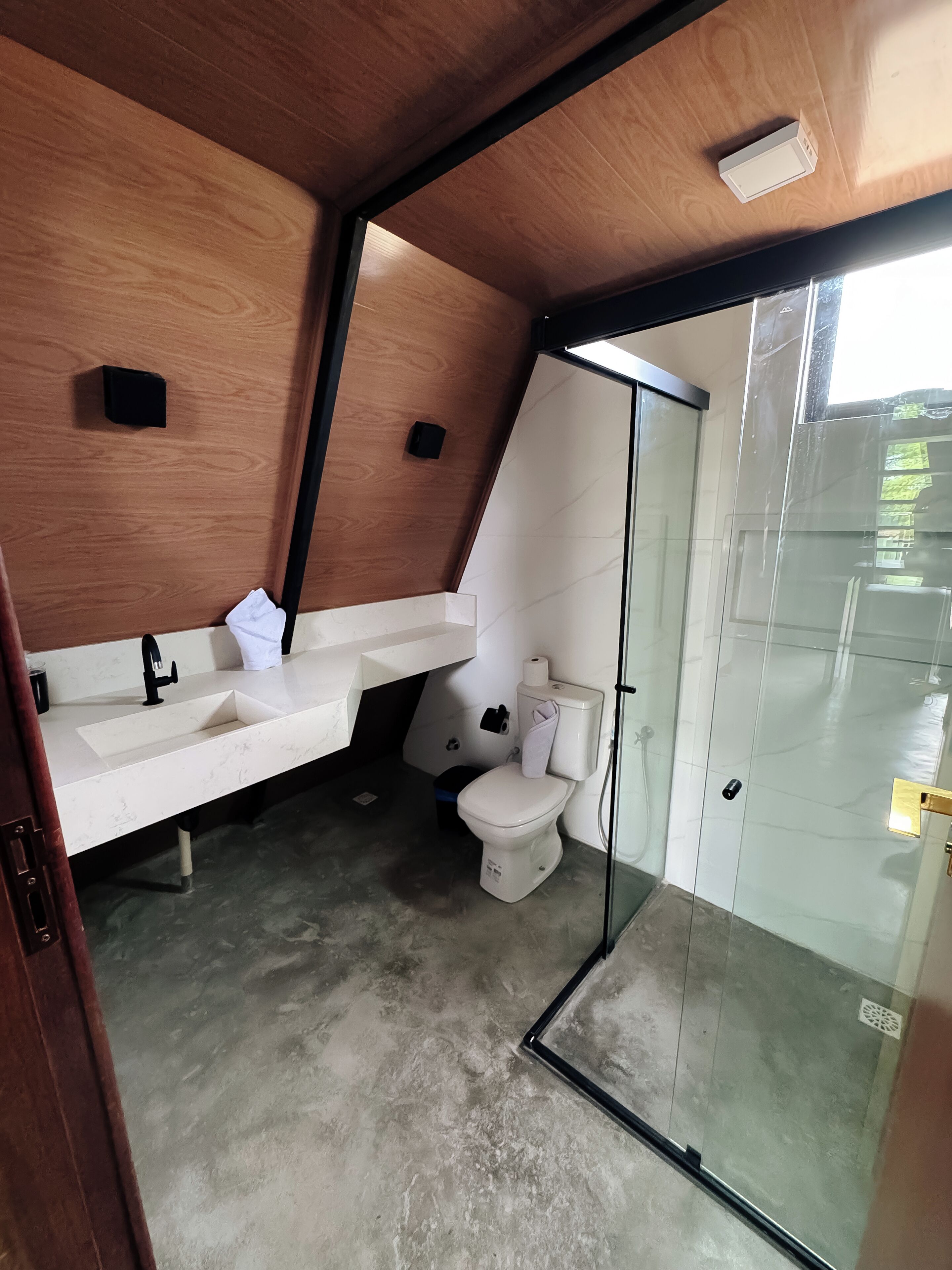 Une salle de bain moderne avec un meuble-lavabo en bois, des toilettes et une cabine de douche en verre.