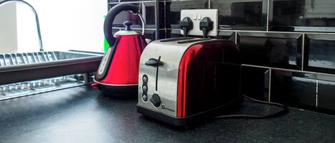 A kitchen counter with a kettle and two toasters.