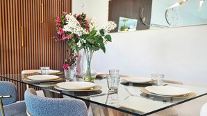 Een eettafel gedekt met borden, glazen en bestek, omringd door gestoffeerde stoelen.