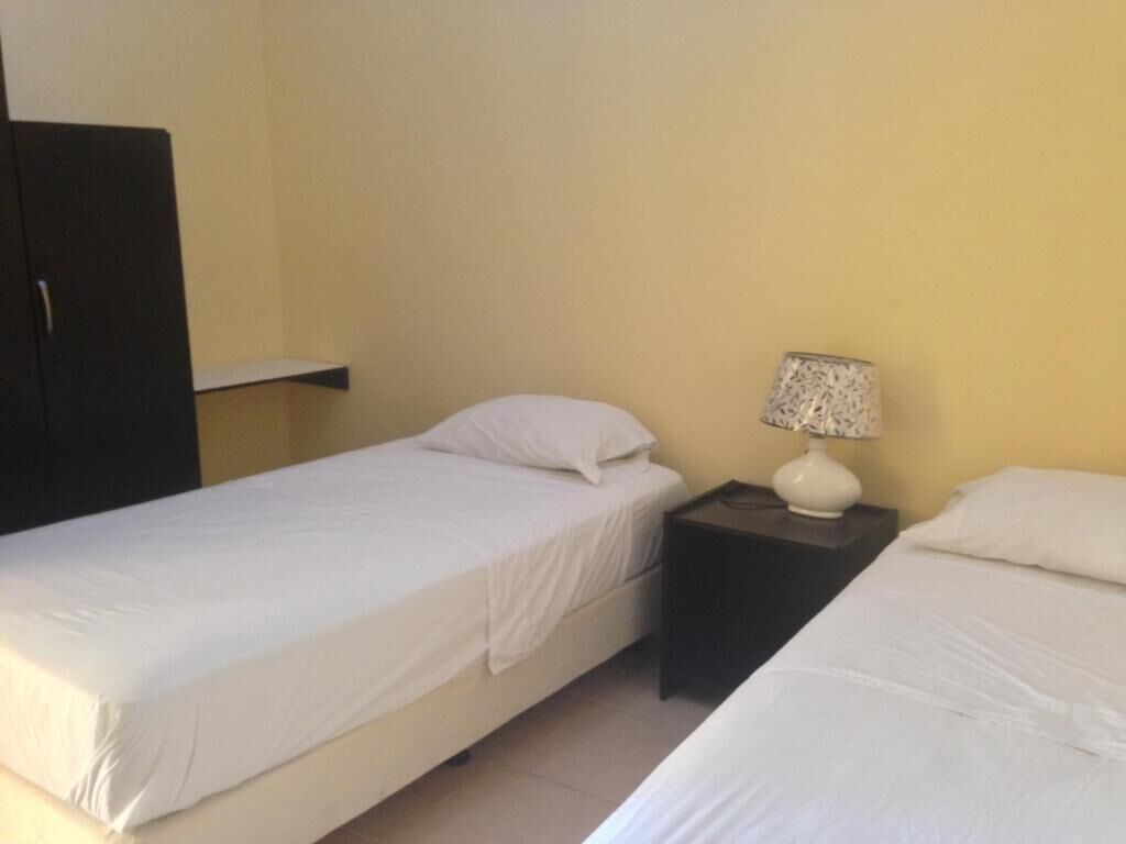 Une chambre avec deux lits simples, une table de chevet avec une lampe et une armoire.