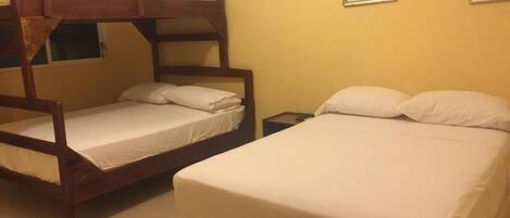 A room with two bunk beds and a single bed, a nightstand, and two framed pictures on the wall.