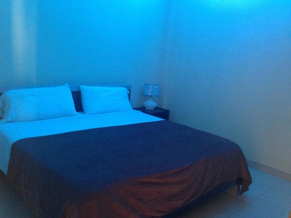 A bedroom with a bed, a nightstand, and a lamp.