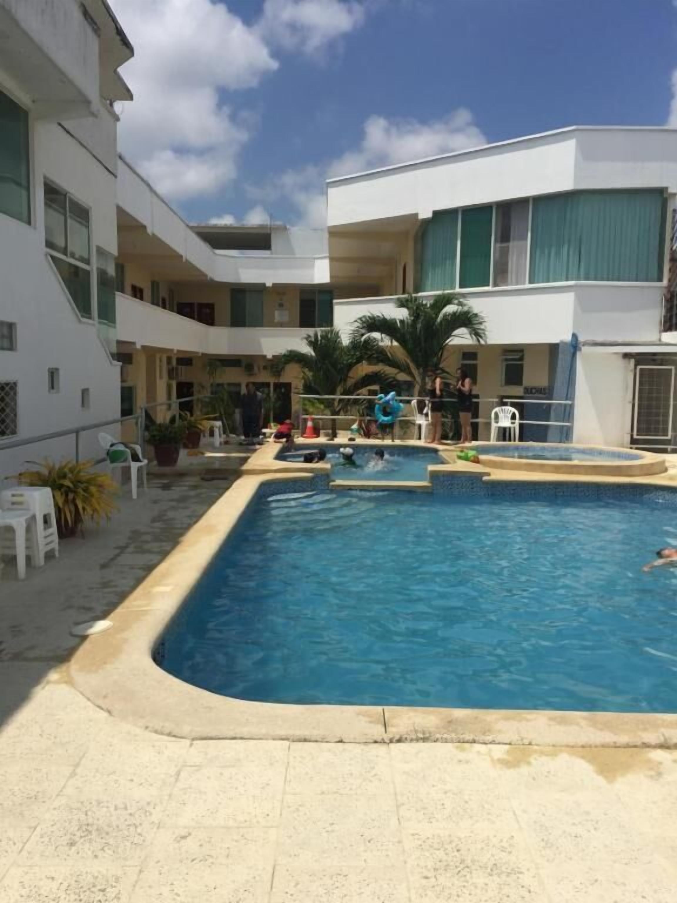 A swimming pool surrounded by a multi-story building with balconies.
