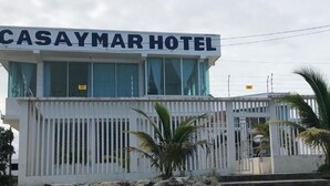 Η εξωτερική όψη του ξενοδοχείου Casaymar, με μια εμφανή επιγραφή, λευκούς εξωτερικούς τοίχους και μια πύλη στην είσοδο.