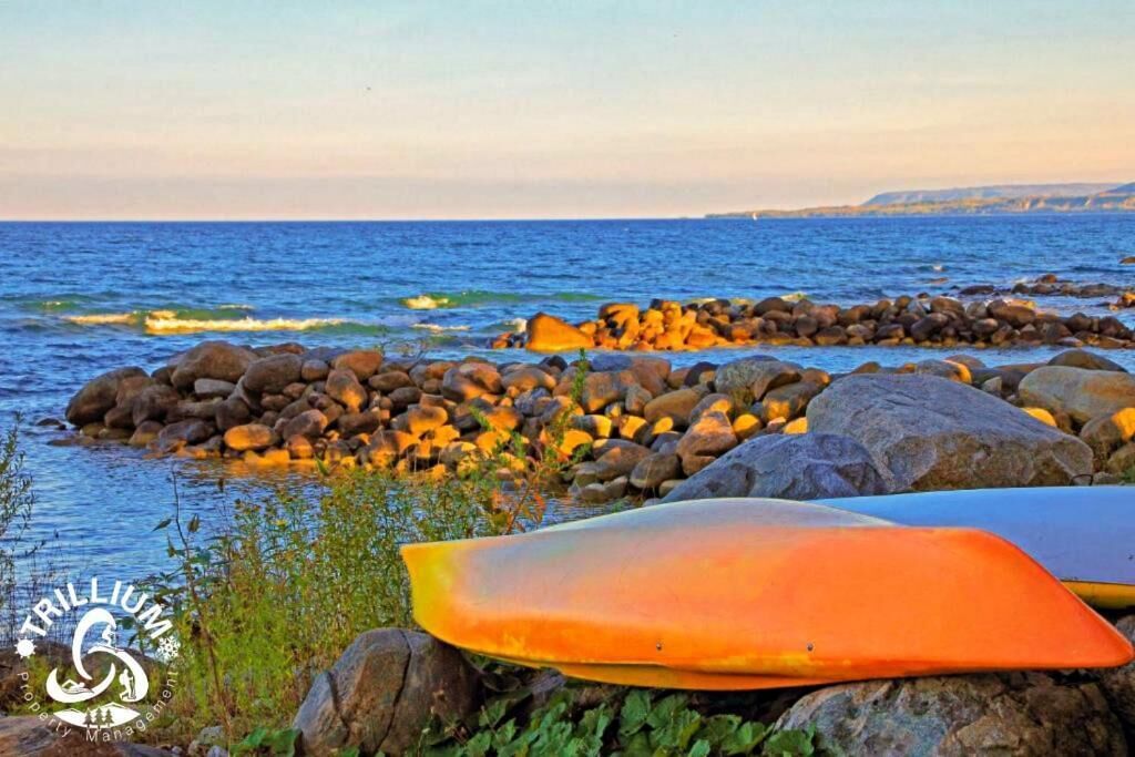 En stenet kystlinje med en surfbræt og en kajak.