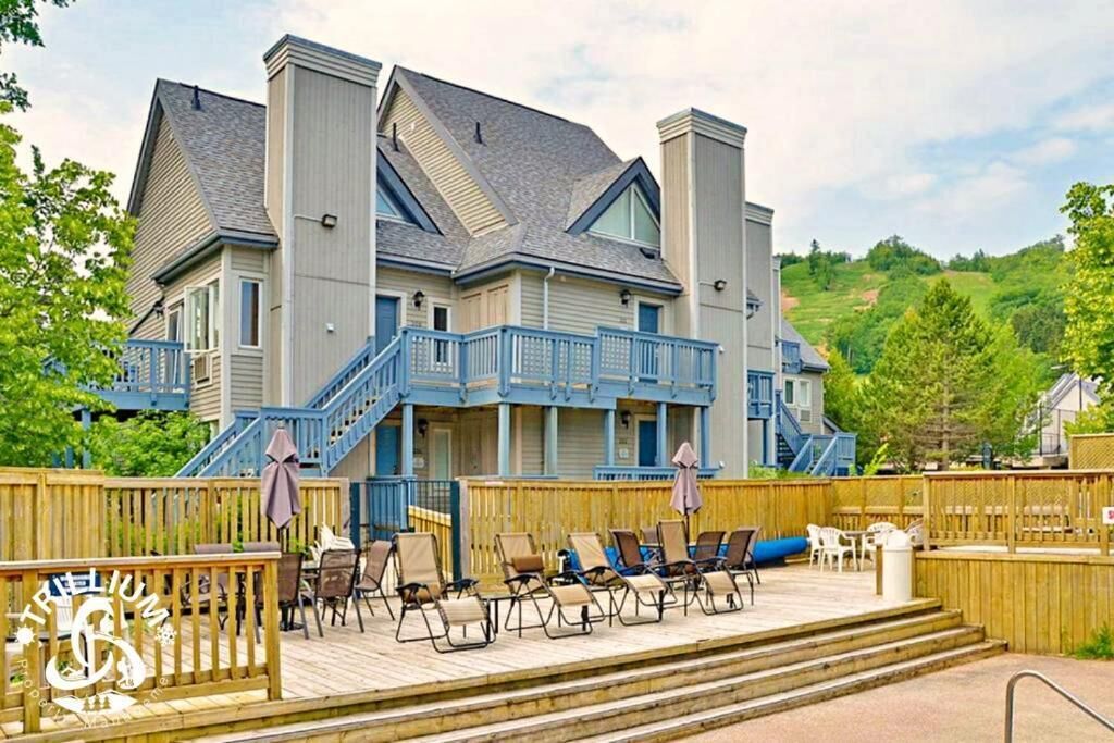 A large house with a deck, outdoor seating, and a staircase leading to the upper floor.