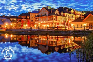 A waterfront property with multiple buildings, a reflective water body, and a logo indicating property management. - Mountainview Loft at North Creek Resort (Blue Mountain)