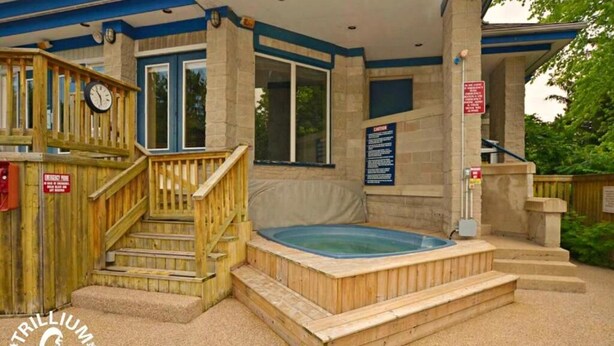 Une terrasse en bois avec un jacuzzi, des escaliers et une horloge.