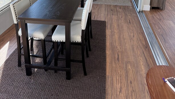 A modern living room with a dark wooden dining table, white cushioned chairs, a round coffee table, and a sofa.