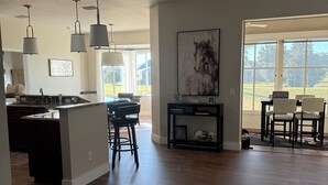 A spacious kitchen with a central island, pendant lights, and a dining area with chairs and a table.