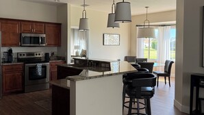 A modern kitchen with dark wood cabinets, stainless steel appliances, and a central island with bar stools.