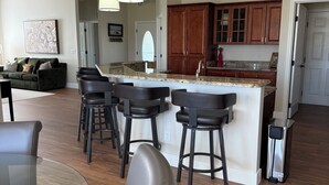 A modern kitchen with a central island, bar stools, and pendant lighting.