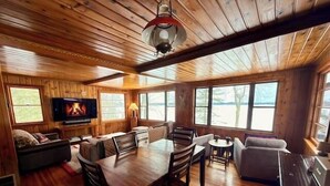 Een gezellig chalet interieur met een houten eettafel, stoelen, een bank en een televisie.