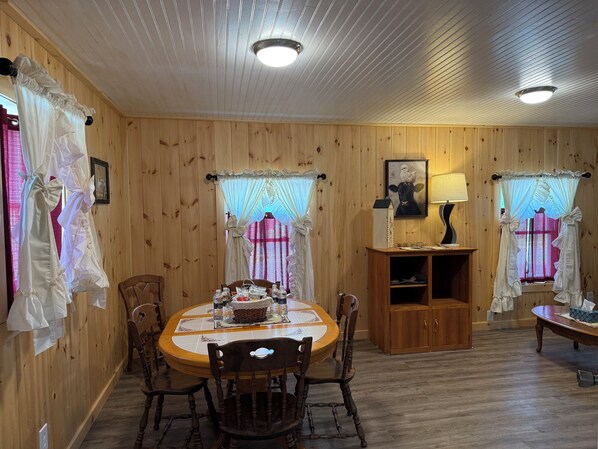 Una habitación con paneles de madera, una mesa redonda para comer, sillas y un armario.
