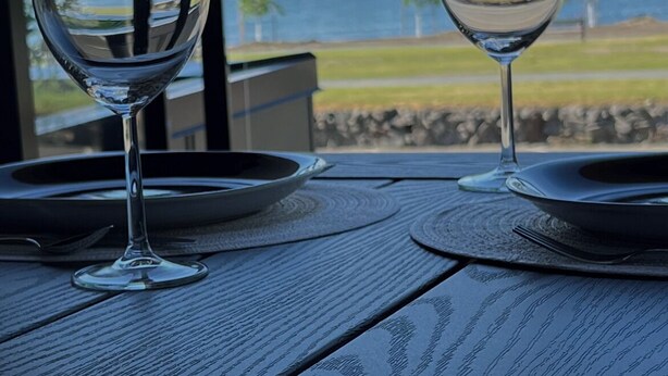 Dos copas de vino sobre una mesa con vistas a un lago y montañas.