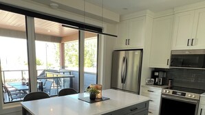 Una cocina moderna con una isla grande, electrodomésticos de acero inoxidable y vistas a un patio exterior.