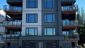 A multi-story residential building with balconies, large windows, and a garage. - THE HUB- NEW Lakefront 3-bed/2-bath suite in Harrison Hot Springs with WiFi, AC. (Harrison Hot Springs)