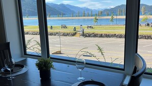 Una mesa de comedor con vista a un lago y montañas a través de amplios ventanales.