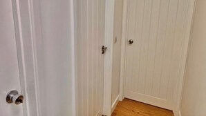 A hallway with a wooden floor and white doors.