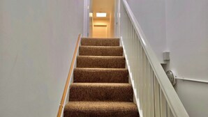 A carpeted staircase with white railings and a light-colored wall.