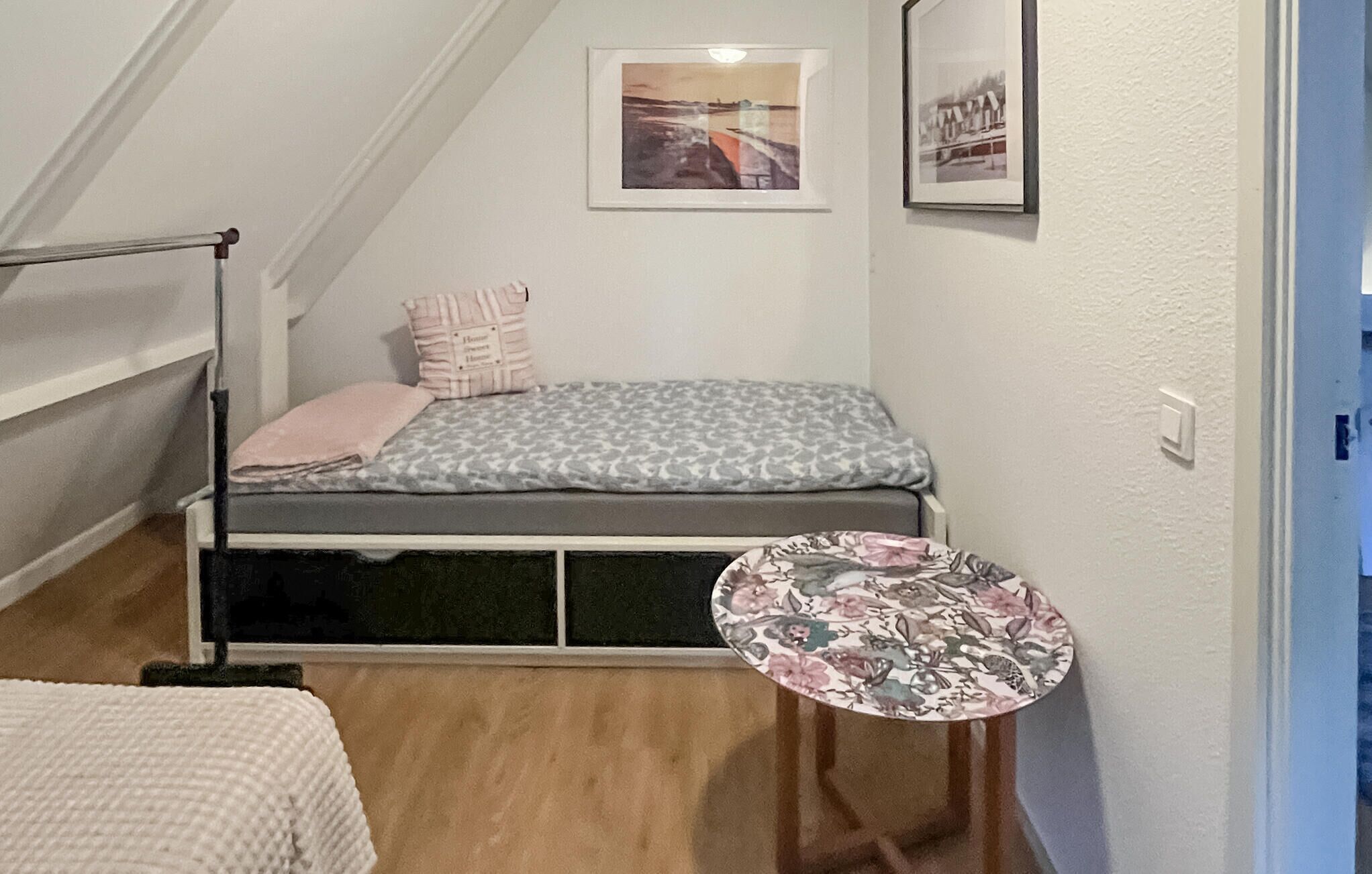 A small, cozy room with a bed, a small table, and a window.