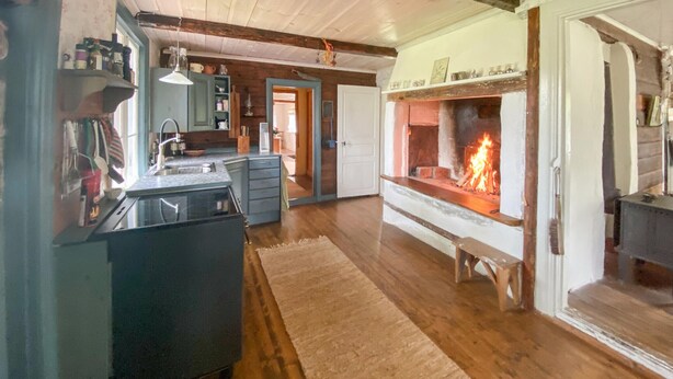 Una cocina acogedora con suelos de madera, estufa empotrada y comedor con banco.