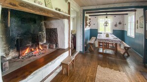 Una habitación rústica con chimenea, un banco de madera y una mesa de comedor preparada para cuatro personas.