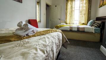 A hotel room with two beds, a red chair, and a window with curtains.