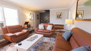 Ein Wohnzimmer mit zwei braunen Ledersofas, einem weißen Couchtisch und einem gemusterten Teppich.