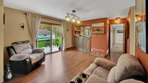 A spacious living room with a sliding glass door leading to a patio, a kitchen area, and a dining area.