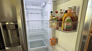 An open refrigerator with a water dispenser, a bottle of Perrins, a bottle of ranch dressing, a bottle of ketchup, and a box of baking soda.