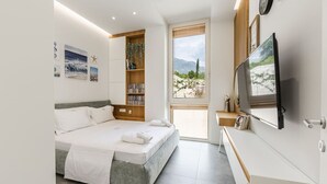 Une chambre à coucher moderne, équipée d’un lit, d’une bibliothèque, d’un téléviseur et offrant une vue sur l’extérieur.