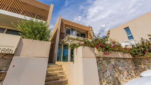 Un bâtiment moderne avec une façade en pierre, un toit à lattes de bois et un escalier menant à l’entrée.
