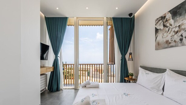Une chambre d’hôtel moderne avec un grand lit, une télévision, un balcon avec des rideaux et un tableau au mur.