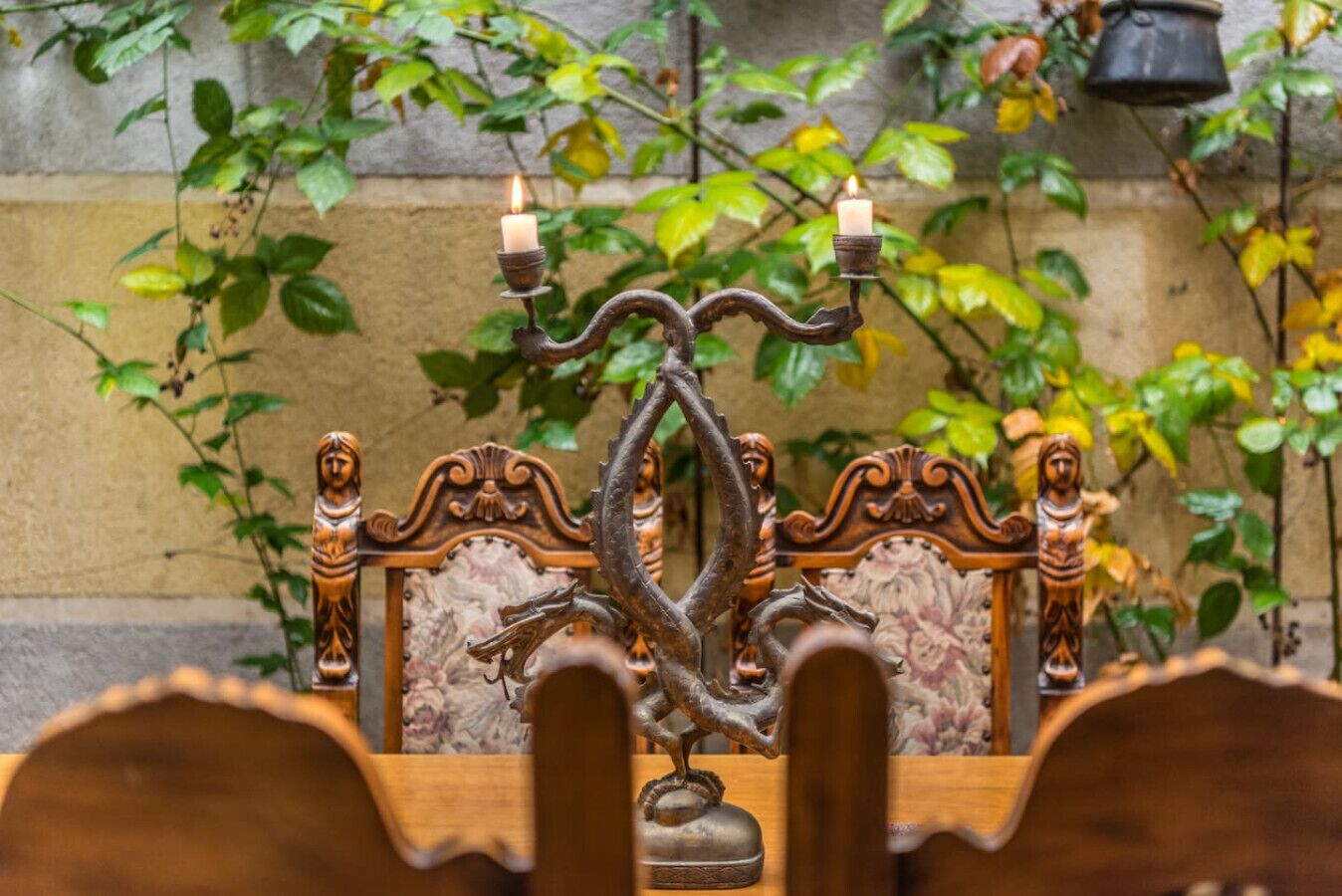 A wrought iron candelabra with candles on a wooden chair with ornate carvings.