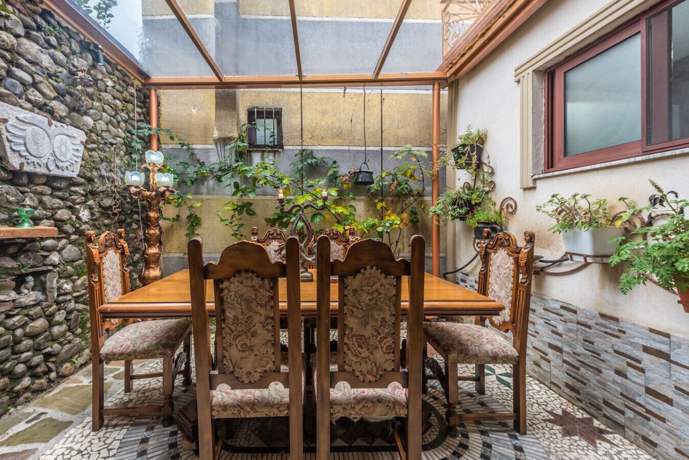A dining area with a stone wall, a wooden table, and chairs with floral upholstery.