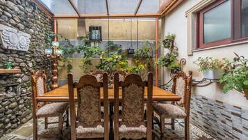 A dining area with a stone wall, a wooden table, and chairs with floral upholstery.