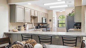 A modern kitchen with granite countertops, stainless steel appliances, and a central island with bar stools. - Cozy Comfort Retreat For 6 (Branson)