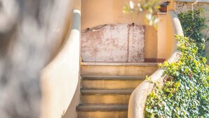Una escalera con una pared de piedra rústica y desgastada, y una barandilla de metal.