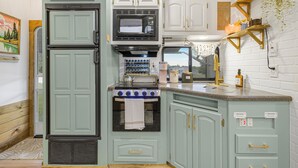 A kitchen with a double-door refrigerator, a microwave, a stove, and a sink. - Tiny Home Near Tetons & Island Park! (Felt)
