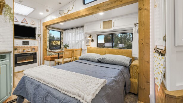 A cozy bedroom with a bed, a television, a window, and a kitchenette. - Tiny Home Near Tetons & Island Park! (Felt)