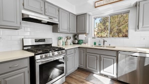 Cozinha moderna com armários cinzas, fogão de aço inoxidável e lava-louças.