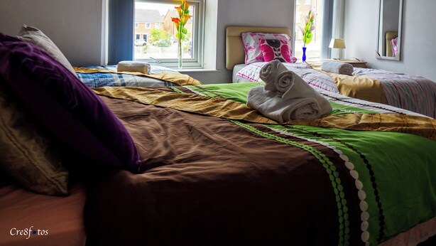 A hotel room with two beds, a large window, and a view of the street. - Bucknall Lodge Family Room 4 Hanley (Stoke-on-Trent)