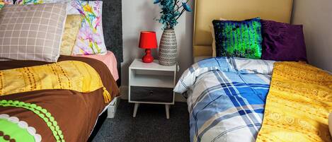A hotel room with two beds, a nightstand with a lamp, and a vase with flowers.
