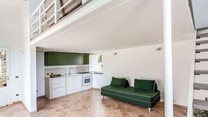 Eine moderne Küche mit weißen Schränken, einem grünen Sofa und einer Treppe, die zu einer oberen Ebene führt.